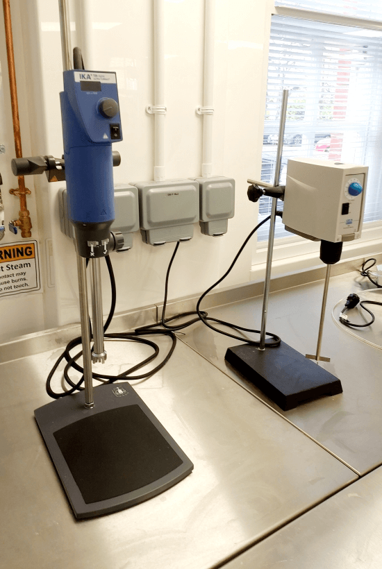On the left, IKA T-25 digital ULTRA-TURRAX disperser with a blue casing. On the right, an LS Overhead Stirrer with an adjustable stand, used for laboratory mixing and stirring processes