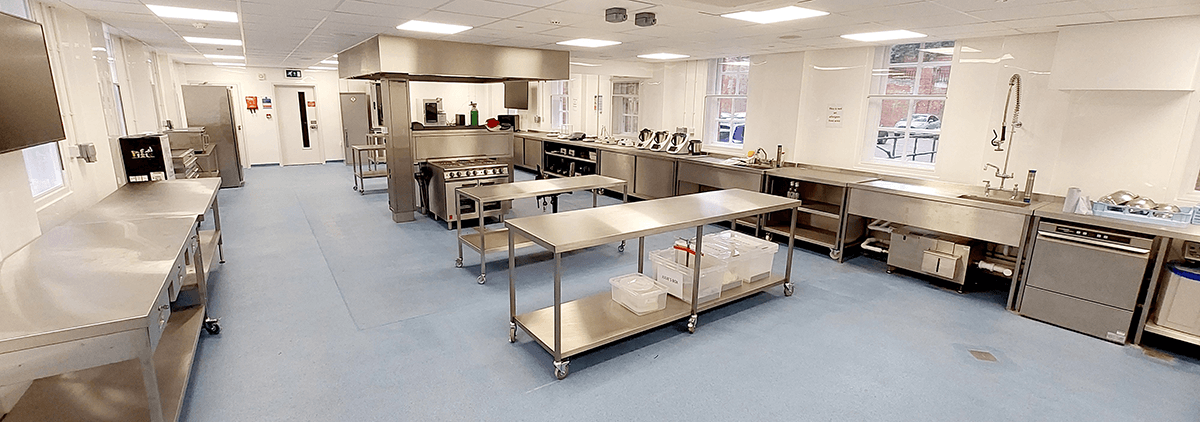 Product development laboratory featuring stainless steel workstations, commercial kitchen equipment, and a spacious layout designed for testing food formulations